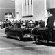 Secret Service agents standing on running boards of a car following the limousine carrying president John F. Kennedy, right, rear seat, and first lady Jacqueline Kennedy, left.